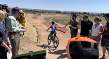 A mountain biker rides through a red ribbon, marking the opening of Cresta Open Space pump track